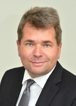 Carsten Rehers Porträt eines Mannes mit kurzer, grauer Frisur, Anzug und Krawatte, vor einem neutralen Hintergrund.