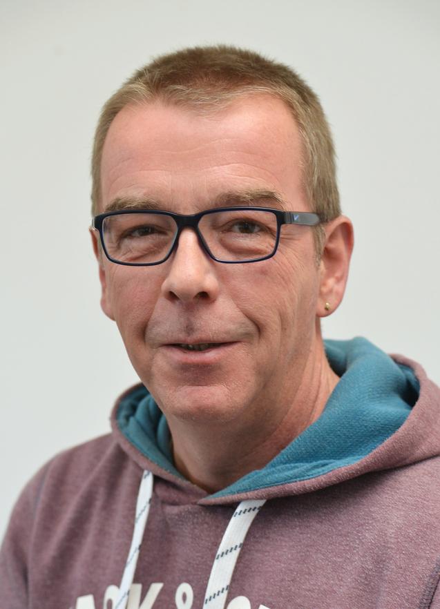 Johannes Wermers Mann mit Brille, kurzen blonden Haaren und einem schlichtem Kapuzenpullover lächelt vor einem hellen Hintergrund.